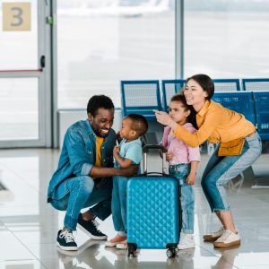 Famille afro-américaine souriante avec des bagages et leurs enfants à l'aéroport